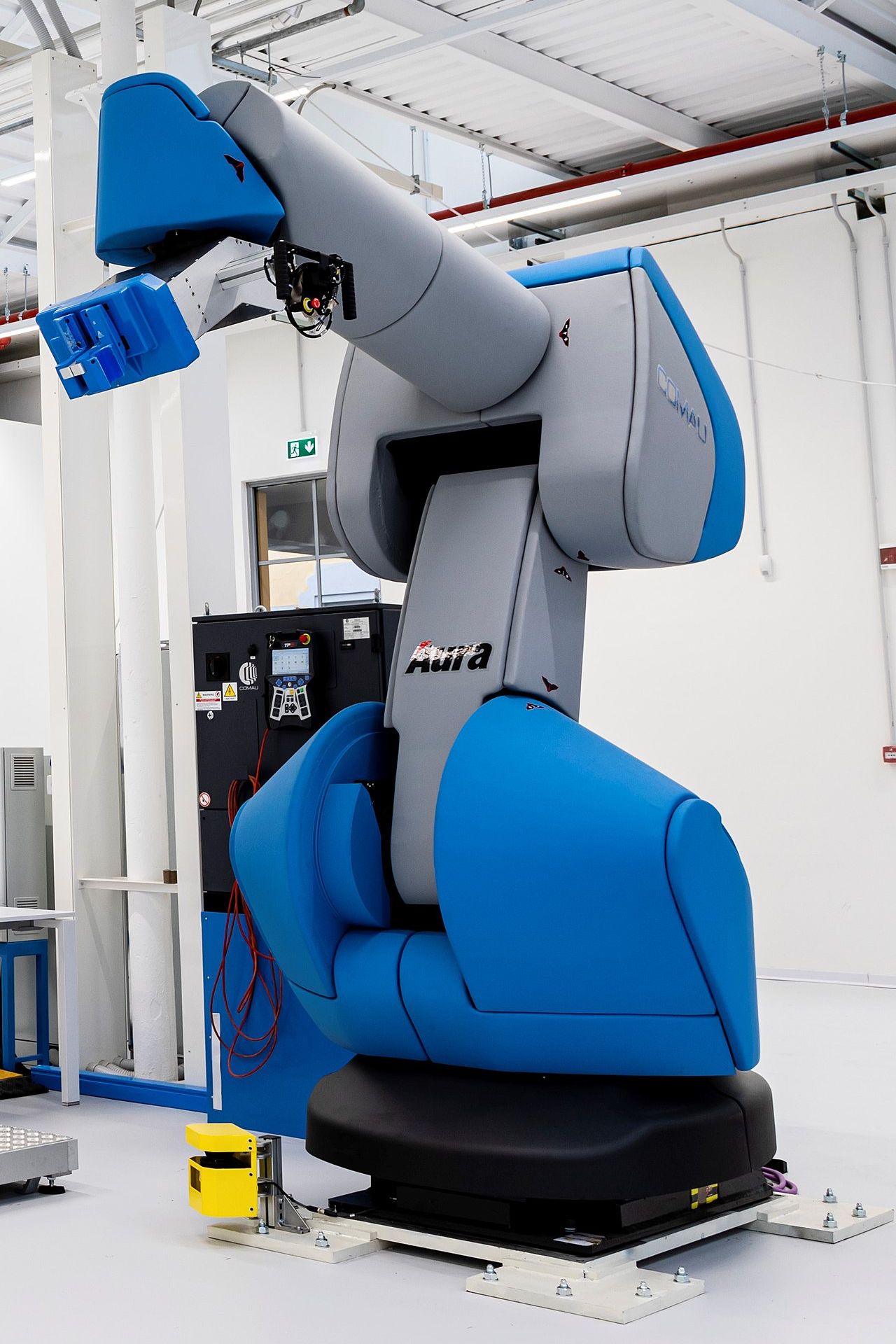 Comau AURA collaborative robot, a high-payload cobot with padded covers, standing uncaged on a demonstration floor.